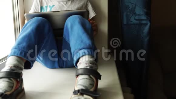 偷东西可爱的男孩玩平板电脑坐在房间的窗台上视频的预览图