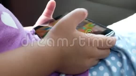 小宝宝手拿智能手机在驾驶汽车上观看视频片段特写视频的预览图