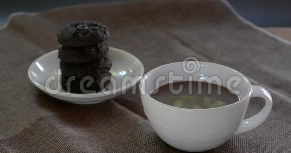 喝热巧克力在白色陶瓷杯与模糊的黑巧克力饼干棕色桌布为每个人提供美味的饮料视频的预览图