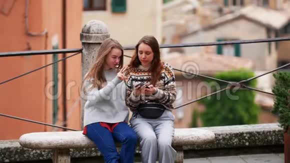 两个年轻的女人坐在长凳上看着结果的照片笑了起来视频的预览图