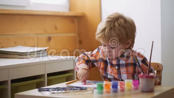 快乐可爱的男孩给他的手涂上颜色做手指画儿童艺术治疗儿童个性心理视频的预览图
