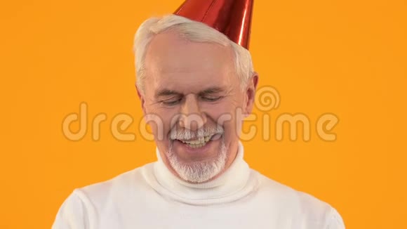 快乐的老人戴着派对帽吹着蛋糕蜡烛享受生日庆典视频的预览图