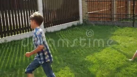 微笑的小男孩笑着沿着绿色的院子草坪奔跑视频的预览图