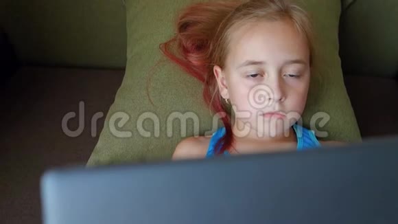 可爱的小女孩拿着数字平板躺在床上十几岁的女孩在平板电脑上玩视频的预览图