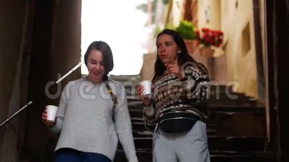 两个年轻女人端着咖啡上楼谈视频的预览图