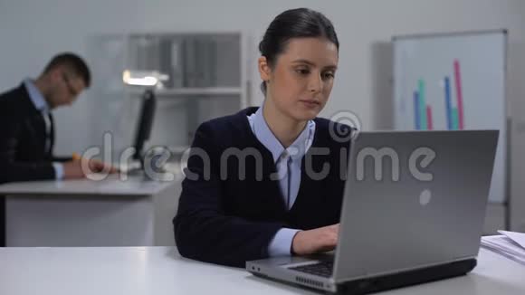 女经理在大公司上班的时候在笔记本电脑上打字前微笑视频的预览图