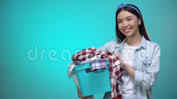 快乐的女人拿着洗衣篮对着镜头微笑文字模板视频的预览图