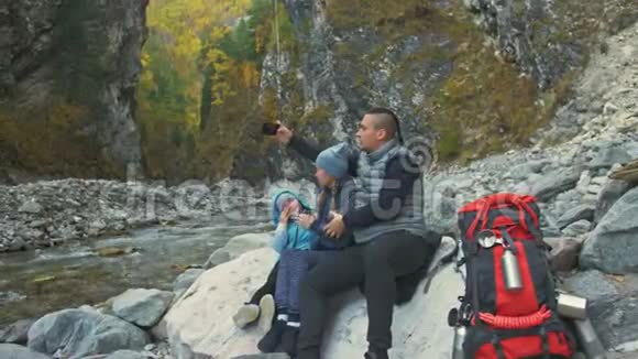 游客徒步旅行后休息在电话里自拍家庭旅行人的环境由河流溪流构成父母视频的预览图