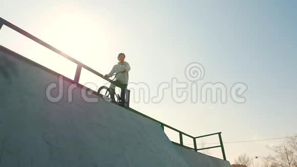 一位穿灰色连帽衫的职业BMX骑手骑着自行车站在上面然后下山视频的预览图