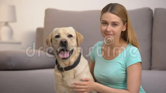 开朗的拉布拉多猎犬女主人微笑着与宠物做伴视频的预览图
