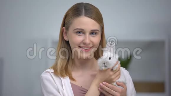 漂亮的女人抱着小兔子对着镜头微笑快乐的宠物主人领养视频的预览图