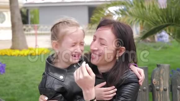 漂亮的母亲抚慰和拥抱哭泣的女婴美丽的年轻母亲在公园里安抚哭泣的女儿视频的预览图