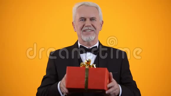 性格开朗的男性退休人员在相机上赠送红色礼品盒生日礼物视频的预览图