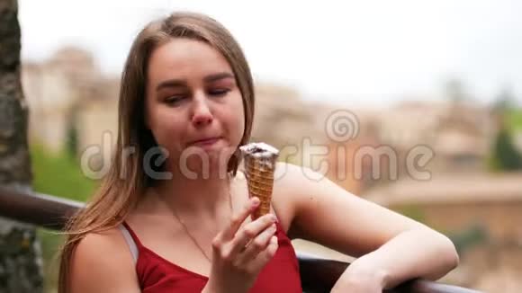 年轻迷人的女人靠在栏杆上吃冰淇淋视频的预览图