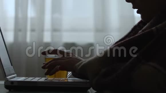 患病妇女喝茶在笔记本电脑上工作季节性流感的剪影视频的预览图