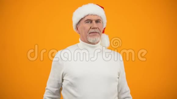 戴着圣诞老人帽子的乐观老人在镜头前微笑新年庆典视频的预览图
