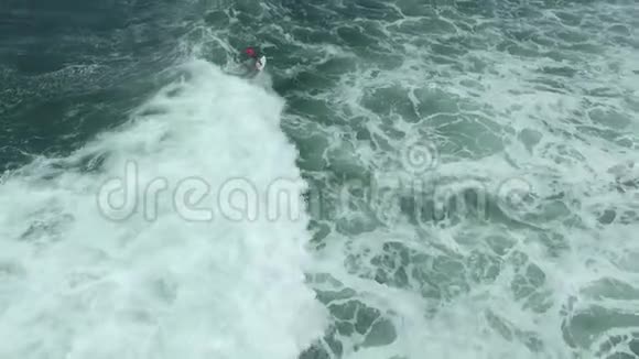 令人惊叹的无人机镜头显示一名女子在海洋中的泡沫海浪中冲浪视频的预览图