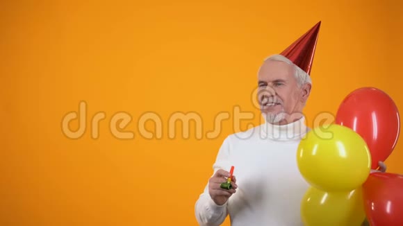 带着彩色气球的开朗的高级男士使用派对鼓风机视频的预览图