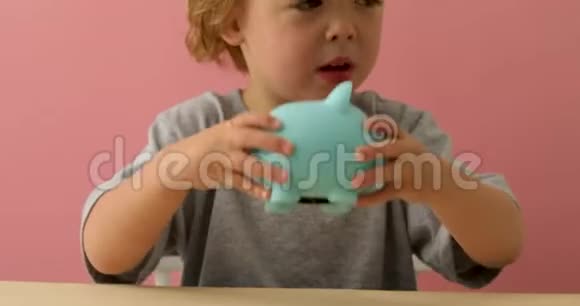 小男孩摇着他的储蓄罐视频的预览图