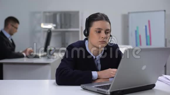 无聊的操作员戴着耳机在工作场所等待客户来电电话推销视频的预览图