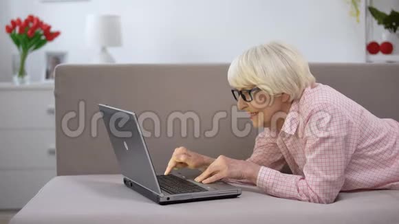 微笑的老年妇女与家人在笔记本电脑上聊天学习社交网络视频的预览图