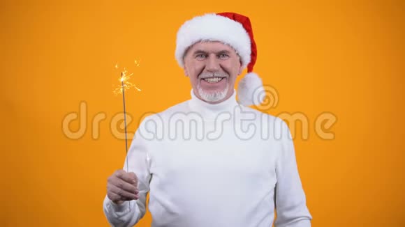 圣诞老人帽子上戴着孟加拉灯的快乐老人在镜头前微笑视频的预览图