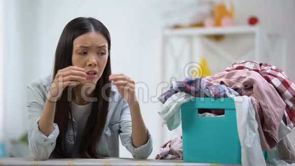 沮丧的家庭主妇看着装满衣服的洗衣篮工作过度视频的预览图