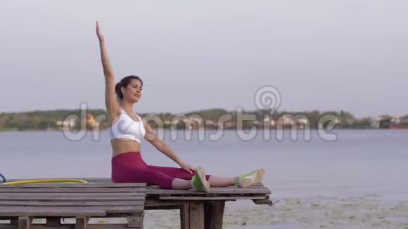 快乐健身女性在桥上自然运动训练中身体向两侧倾斜进行伸展运动视频的预览图