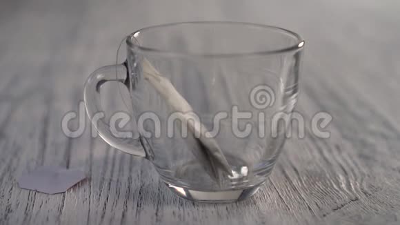 热水倒在一个杯子里杯子里放着一袋凉茶放在灰色的木桌上视频的预览图