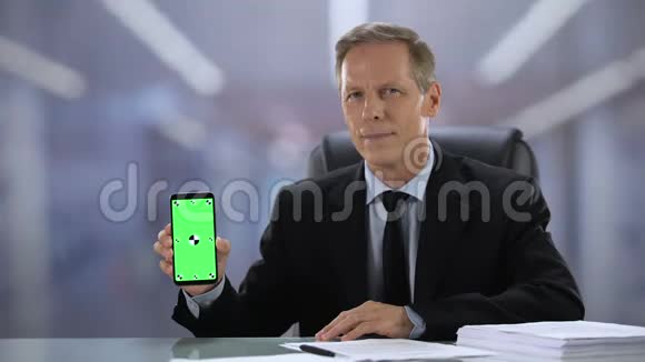 穿着绿色屏幕智能手机相机商务应用程序的快乐男老板视频的预览图