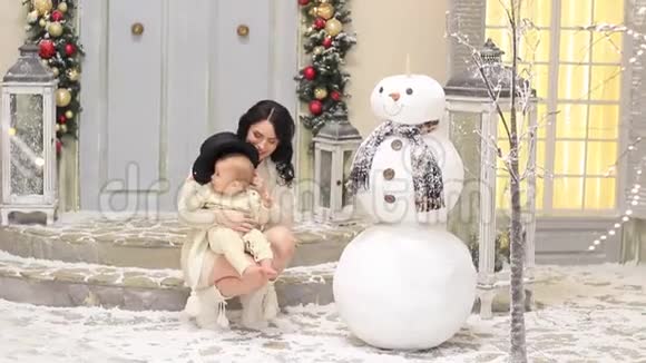 年轻的妈妈和她的小宝宝在圣诞节堆雪人视频的预览图