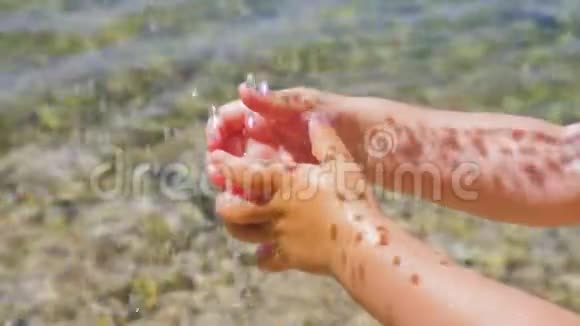 饮用水滴在孩子的手上小手玩着水珠水中的光和影视频的预览图