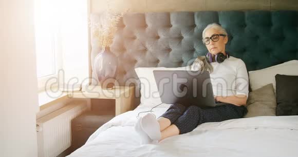 卧室里有笔记本电脑的老年妇女视频的预览图