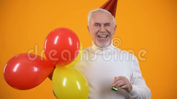 很高兴男性退休者使用派对鼓风机和手持五颜六色的气球生日视频的预览图