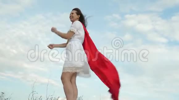 穿着红色斗篷站在球场上的女孩扮演超级英雄开朗的女人穿着红色斗篷表情开朗视频的预览图