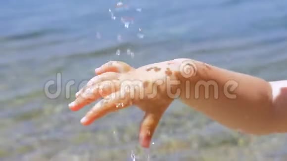 孩子们的手在水滴下阳光反射在皮肤上水滴落在海边的小手上视频的预览图