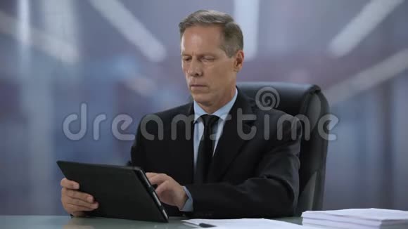 自信的男老板在办公桌上做平板电脑在线文档视频的预览图
