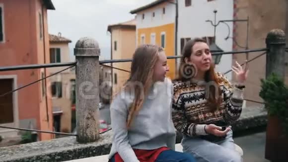 两个年轻的女人坐在街上说话其中一个展示给另一个视频的预览图