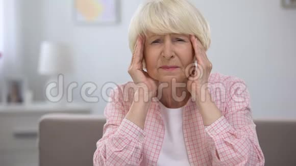 老年妇女按摩太阳穴感觉偏头痛健康问题视频的预览图