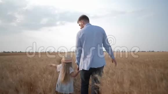 一家人在田里散步年轻的父亲和小女儿一起散步抚摸着阳光明媚的小麦穗视频的预览图