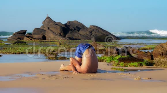 肌肉运动员在湿沙上做瑜伽姿势视频的预览图