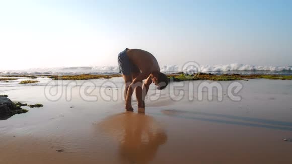 穿蓝色短裤的肌肉男在沙滩上伸展视频的预览图