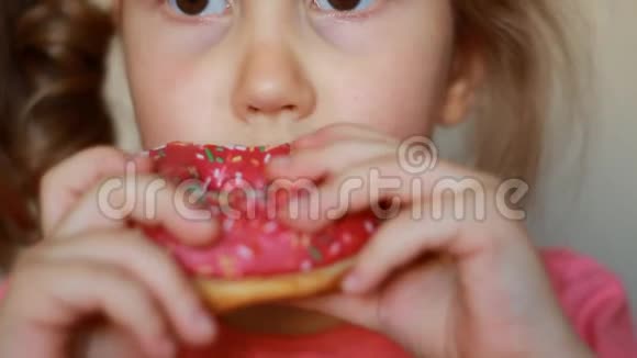 小孩嘴咬玫瑰甜甜圈特写小女孩吃甜甜圈加糖好吃的甜的甜的视频的预览图