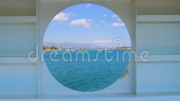 从一个带有圆形窥视孔窗口的船舱内可以看到希腊的城市夏季景观破旧的圆窗视频的预览图
