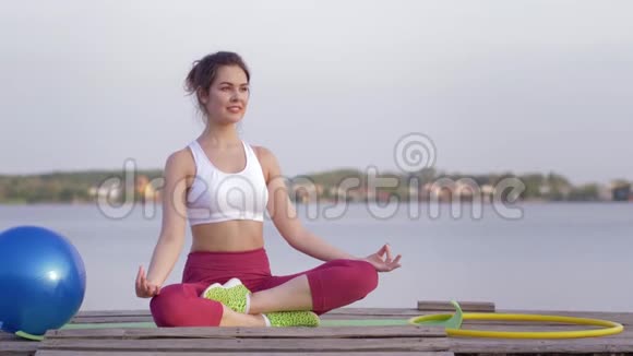 瑜伽放松年轻迷人的瑜伽女孩在莲花的位置冥想和快乐的精神平静的自然视频的预览图