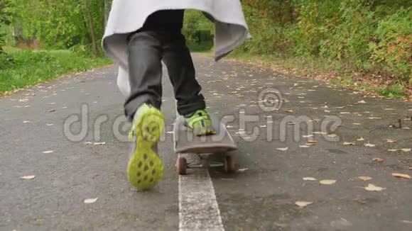 少年儿童滑板在城市公园后景在绿色的夏天少年少年骑着滑板上路视频的预览图