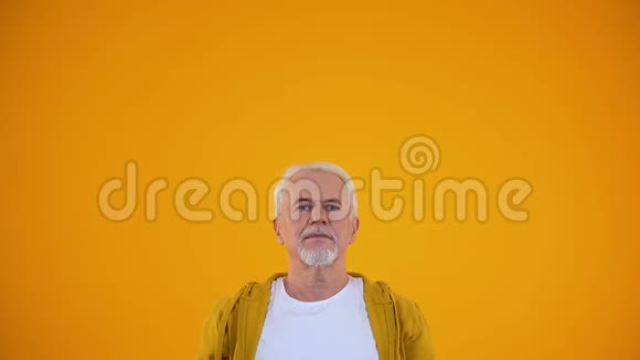 快乐的退休男子伸出双手庆祝橙色背景下的成功视频的预览图