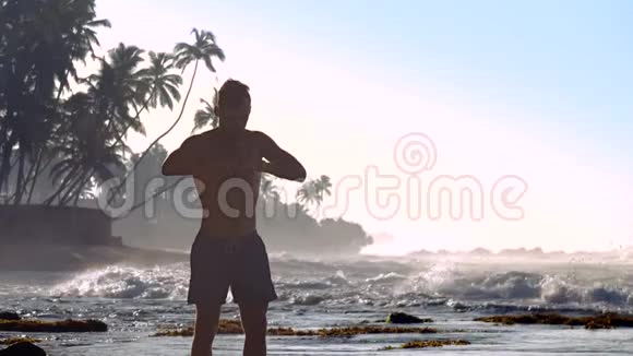 英俊的男人在海洋海岸上冥想对抗起泡的波浪视频的预览图
