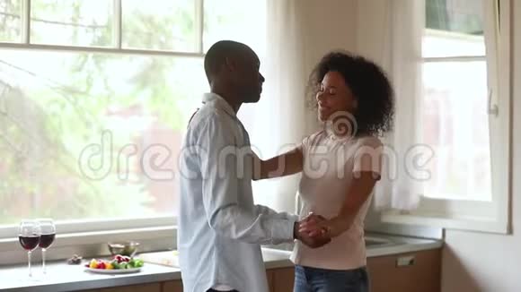 快乐浪漫的年轻非裔美国夫妇在厨房跳舞视频的预览图