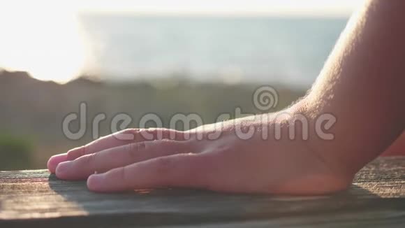 模糊的海洋背景前景中有一个木制长凳上面躺着一个孩子的手掌视频的预览图